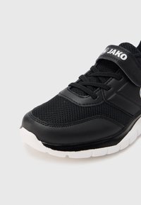 Pantof sportiv negru cu partea superioară din plasa și accente sintetice. Include șireturi negre și o baretă cu Velcro, cu o talpă albă pentru contrast.