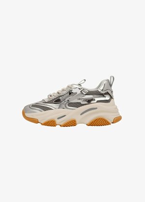 Kengät, joissa on paksu hopeanhohtoinen ja verkko-osa, beige paksu pohja, oranssi kumipohja ja "Steve Madden" -brändäys sivulla.