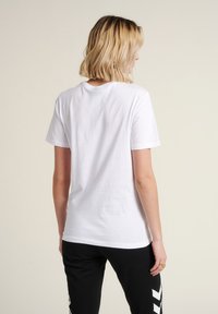 T-shirt en coton blanc avec une coupe classique, des manches courtes et un col rond, présenté de l'arrière. Design simple avec des détails minimaux.
