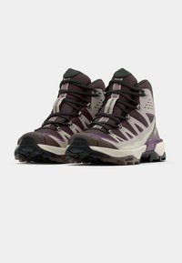 Παπούτσια πεζοπορίας με μέσο ύψος σε μοβ, άσπρο και γκρι. Διαθέτουν ανθεκτική σόλα, ενισχυμένη μύτη και περίπλοκο σύστημα κορδονιών για ασφαλή εφαρμογή.