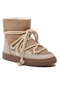 Beige suède enkellaars met een zachte bovenkant, gestructureerde gevlochten veters en rubberen zool. Kenmerkt zich door een ronde neus en een gevoerde schacht voor comfort.