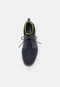 Navy blue casual shoe with mesh texture, smooth upper, round toe, flat laces, and contrasting green insole visible from above.