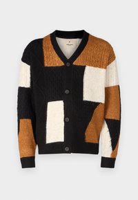 Dzianinowy kardigan z dekoltem w serek, zapięciem na guziki oraz wzorem patchworkowym w kolorach czarnym, brązowym, kremowym i o fakturze tkaniny.
