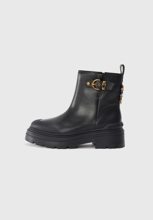 Bottines en cuir noir à bout rond et semelle en caoutchouc épaisse. Présentent des accents en métal doré et une languette. Texture lisse.