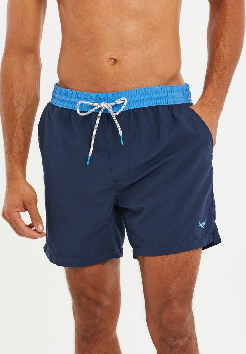 Marineblauwe zwembroek met een elastische tailleband en lichtblauwe trekkoord. Voorzien van zijzakken en een klein logo op de zoom.