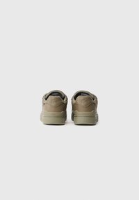 Sneaker marroni e verdi oliva in pelle liscia, con colletto imbottito, punta arrotondata e suole di gomma a contrasto. Presentano il logo sul tallone.