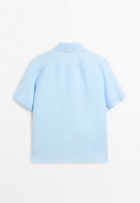 Chemise bleu clair à manches courtes avec une couture droite dans le dos et un col simple, posée à plat sur un fond blanc.