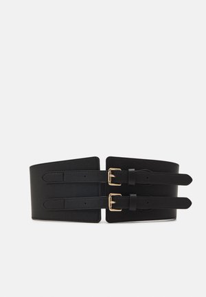 Black faux leather waist belt features two adjustable straps with gold-tone buckles, smooth texture, and a wide design that tapers at the edges.