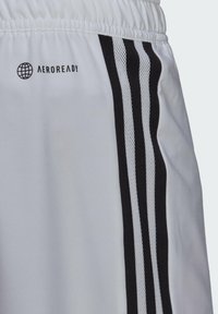 Witte sportshorts met een gestructureerde tailleband, voorzien van drie zwarte strepen aan de zijkant en een "AEROREADY" logo. Gladde stof.