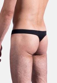 Perizoma da uomo nero, caratterizzato da un design a vita bassa, un tessuto morbido e una copertura minima con una textura liscia.