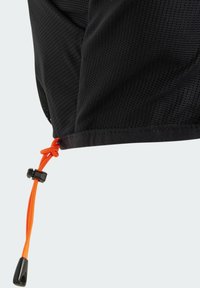 Abrigo exterior de tejido negro con un acabado texturizado, que incluye un cordón naranja y un regulador en el dobladillo para un ajuste personalizable.