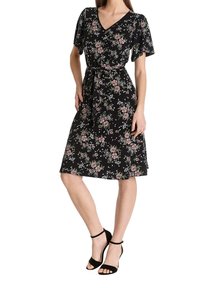 Vestido negro de flores con mangas cortas, escote en V y cinturón. El patrón floral presenta flores rosas y blancas con hojas verdes. Silueta en A.
