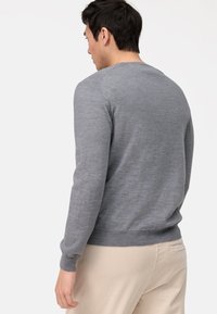 Grijze gebreide trui met lange mouwen, ronde hals, gestructureerde stof en geribbelde tailleband, gecombineerd met beige corduroy broek.