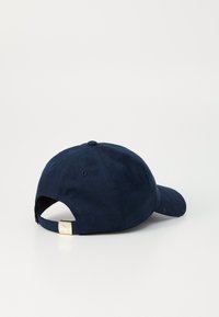 Navy blue cap made of textured fabric with a curved brim; features an adjustable strap with gold-tone hardware at the back.