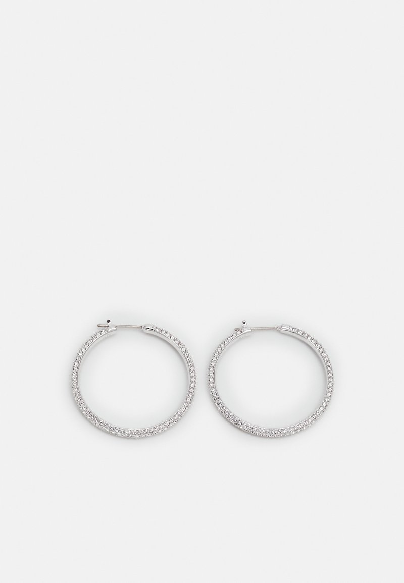 Boucles d'oreilles créoles en argent incrustées de petits strass transparents, présentées sur un fond gris clair uni.