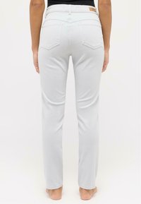 Light gray jeans with a straight-leg design, five-pocket styling, and a leather logo patch on the back waistband. Soft denim texture.