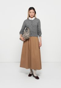 Grijze wollen cardigan, bruine A-lijn rok, crème blouse, handtas met slangenprint en bordeaux loafers, met een gladde textuur en knoopdetails.