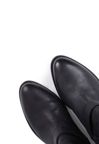 Paire de bottines en cuir noir à bouts arrondis sur fond blanc.