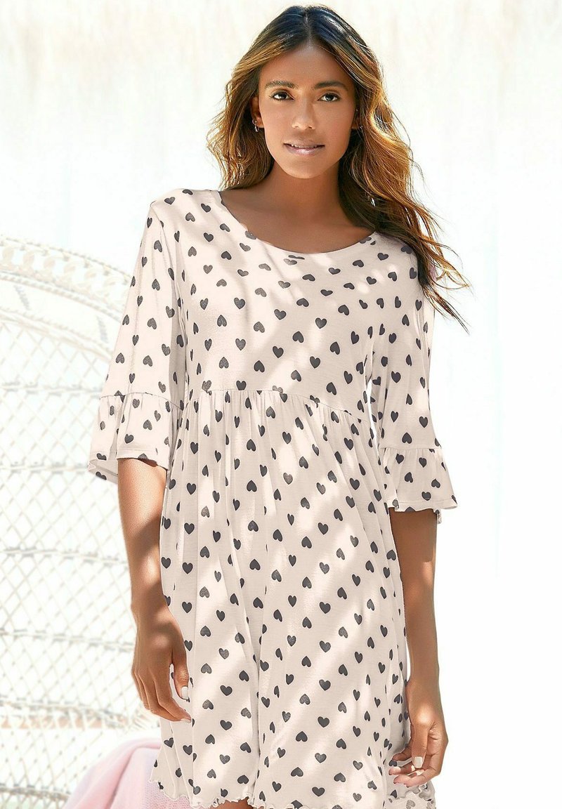 Lightweight, beige dress with black heart patterns, short ruffled sleeves, and a loose fit. Features a round neckline and gathered waist detail.