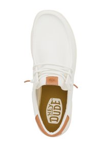 Scarpa di tela bianca con punta arrotondata, lacci elastici e un accento in pelle beige sul tallone. Presenta una soletta marrone con il logo "HEY DUDE".