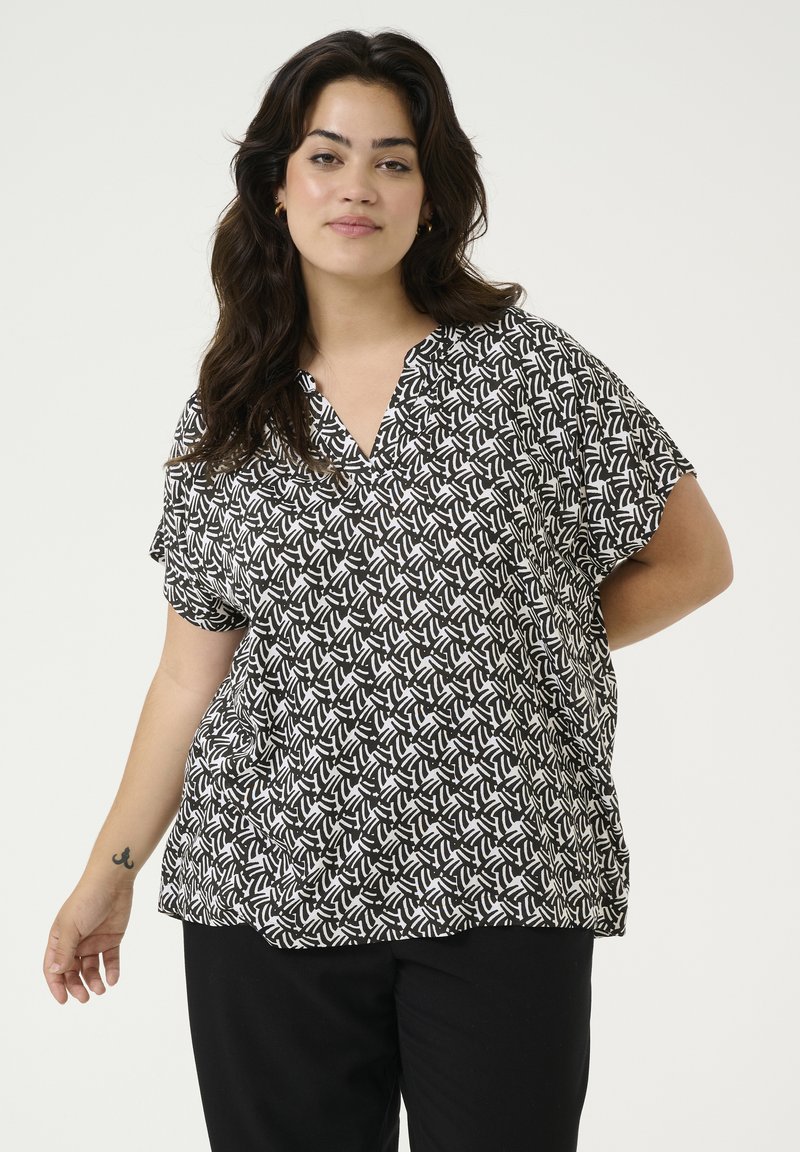 Blouse à manches courtes noire et blanche à motifs avec un décolleté en V, offrant une coupe ample et un tissu doux.