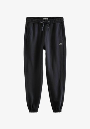 Černé tepláky vyrobené z měkké tkaniny, vybavené elastickým pasem se stahovací šňůrkou, bočními kapsami a malým logem "self." na přední straně.