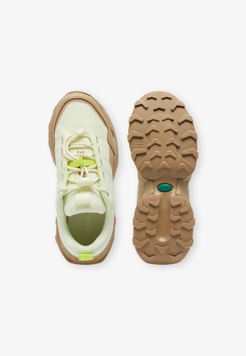 Scarpe sportive con lacci in rete giallo chiaro, con una suola in gomma texturizzata color beige, caratterizzate da un accento verde sulla linguetta e un dettaglio del logo.