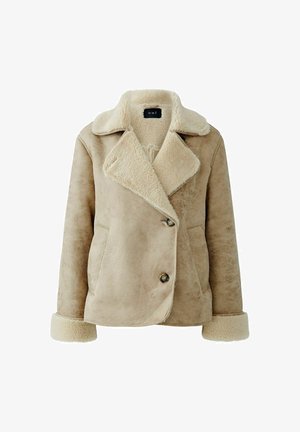 Beige Kunstschaffelljacke mit großem Kragen, doppelt geknöpftem Design, zwei vorderen Taschen und weicher Textur. Knopfdetails vorne.