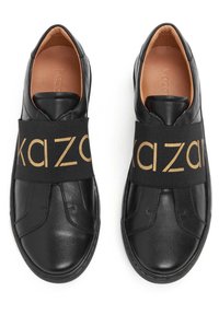 Černé kožené boty na slip-on s elastickým páskem s nápisem "kazar" ve zlaté barvě. Hladký povrch, zaoblená špička, plochá gumová podrážka. Minimalistický design.