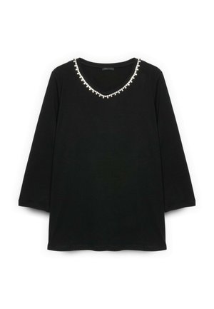 Haut noir à manches longues avec un décolleté en V orné de petites perles blanches autour du cou.