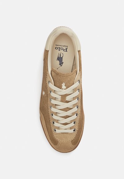 Καφέ σουέντ αθλητικό παπούτσι με μποέζ δερμάτινο γιακά, κρεμ κορδόνια και λεπτομέρεια λογότυπου. Διαθέτει υφασμένο σχέδιο και ελαστική σόλα.