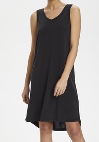 Černé bezramínkové šaty s V-výstřihem, volným střihem a mírně zaobleným lemem. Vyrobeny z měkké, lehké látky.