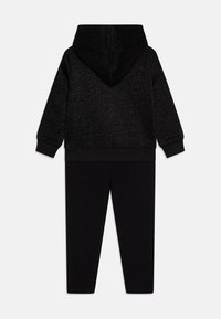 Černý dětský teplákový komplet obsahující mikinu s kapucí a pružnými manžetami a odpovídající kalhoty s úzkým střihem. Měkká textura, minimalistický design.