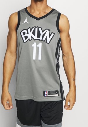 Camiseta de baloncesto gris con detalles en negro, que presenta un gran texto "BKLYN" y el número "11" en blanco. Hecha de un tejido de malla transpirable.