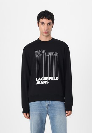 Black sweatshirt with white branded text. Features a crew neck, long sleeves, and a relaxed fit. Soft fabric with a smooth texture.