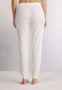 Witte geribde loungebroek met elastische tailleband en boorden, met een zachte textuur en een ontspannen pasvorm.