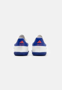 Zapatillas deportivas blancas con acentos azules, que cuentan con una parte superior texturizada, suela de goma y un logo rojo en el talón con el detalle "COPA PURE".