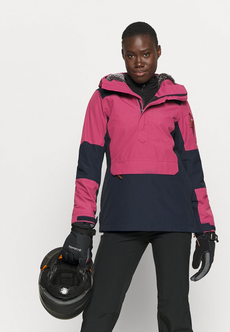 Różowa i granatowa wodoodporna kurtka narciarska z kapturem, pół-zamek z przodu, elastyczne mankiety i dwie kieszenie na zamek. W komplecie czarne spodnie narciarskie i rękawice.