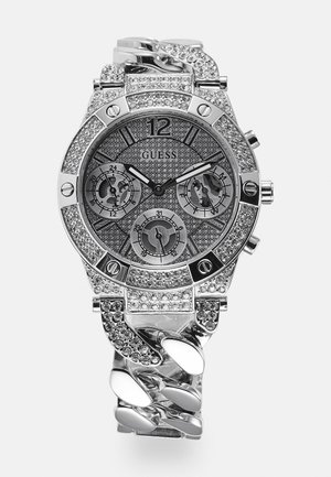 Reloj de pulsera Guess plateado con adornos de cristal, tres subesferas, brazalete grande enlazado y manecillas de hora y minuto negras sobre una esfera texturizada.