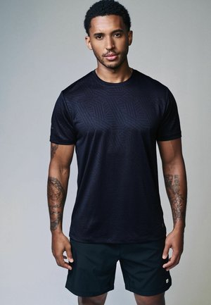 Sort atletisk T-shirt med et geometrisk mønster, lavet af letvægtsmateriale. Bæres med sorte shorts, der har en lille logo-detalje.
