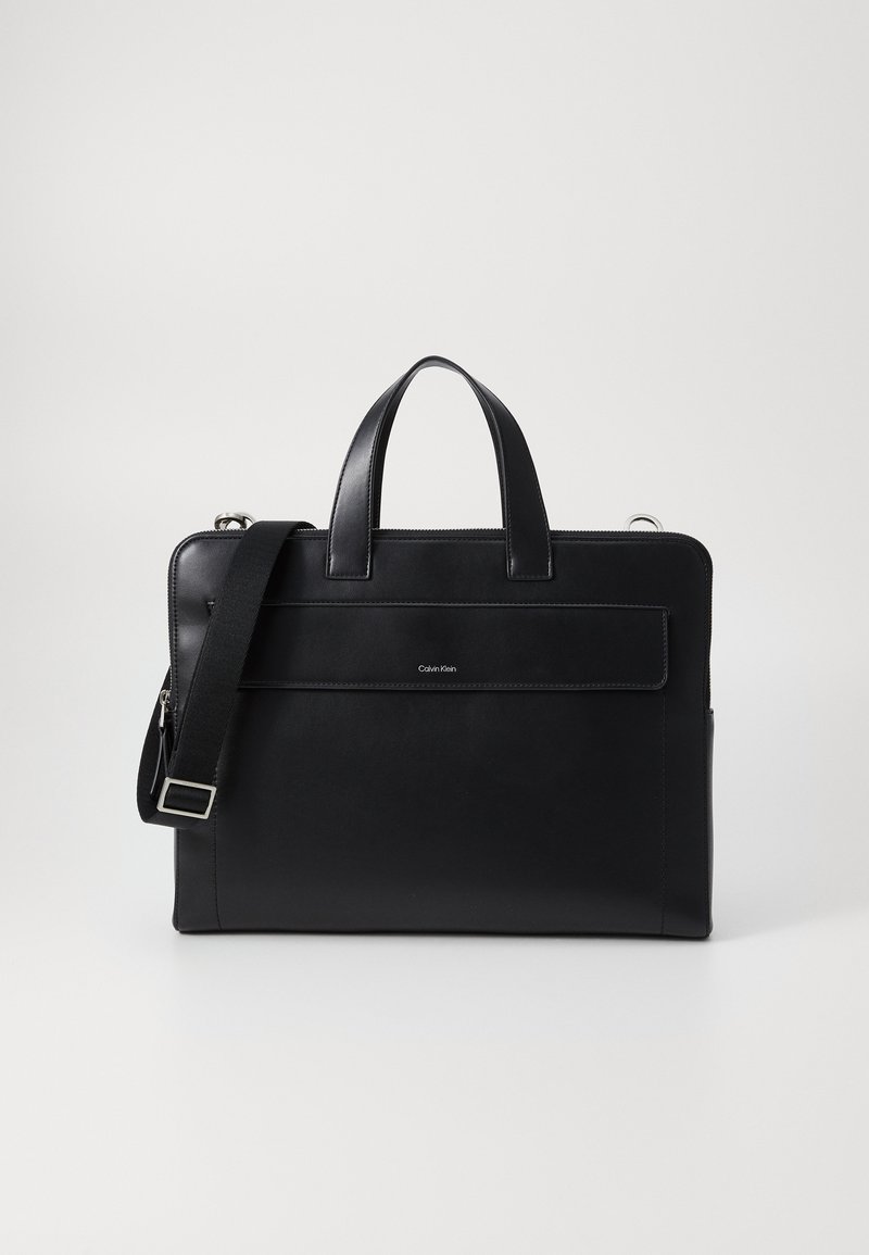 Svart läderportfölj med två handtag, avtagbar axelrem, framficka med lock och liten Calvin Klein-logotyp.