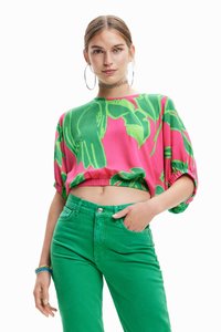 Kortærmet, cropped top i pink og grøn med blomsterdesign; parret med grønne denimbukser med knaplukning og lommer.
