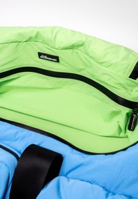 Sac en tissu léger bleu et vert avec une ouverture zippée, des accents noirs et une poche intérieure portant une étiquette de marque.