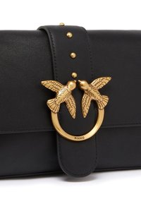Borsa a tracolla in pelle nera con chiusura a forma di uccello in tonalità oro. Presenta un manico decorato con borchie dorate e una texture liscia. Logo del marchio visibile.