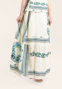 Weiße Maxiröhre mit grünen und blauen Blumenmustern. Verfügt über ein gestuftes Design und geometrische Bordüren. Hergestellt aus leichtem Stoff.
