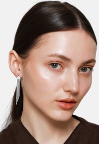 Orecchini multipli in argento con un design geometrico, caratterizzati da catene di metallo allungate che pendono con grazia.