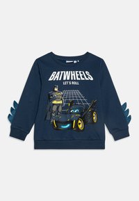 Mornarocrna dukserica s grafikom koja prikazuje Batmana i automobil. Ima teksturirane plave akcenta na rukavima i bijeli natpis "BATWHEELS, KREĆEMO SE."