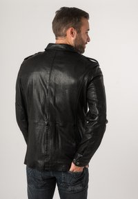Giacca di pelle nera con finitura testurizzata, dotata di colletto alto, spalline sulle spalle e design aderente. Vista posteriore mostrata.
