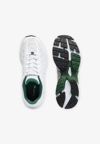 Vita sportskor i vitt med texturerad ovandel, gröna detaljer och svarts gummisula med mönstrad grepp. Fodrad insida för komfort.