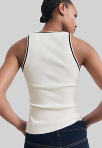 Rippenträgershirt in Off-White mit schwarzem Kontrast, in taillierter Form und mit rundem Ausschnitt, von hinten dargestellt.